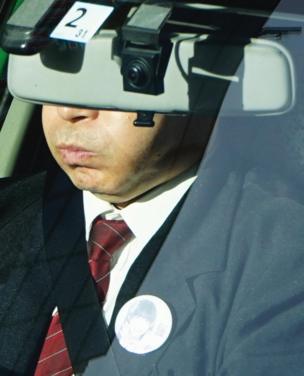 A taxi driver's eyes are covered by a windscreen mirror