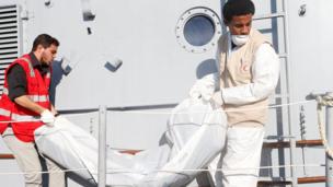 Libyan Red Crescent workers carry a bag containing a body of a migrant who died when a boat sank off Libya