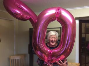 Smiling lady posed behind her birthday balloons