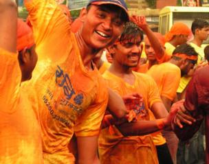 A group of men painted orange and dancing in the rain