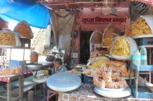 A man prepares food in a street stall fall of snacks