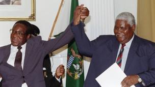 Zimbabwe's President Robert Mugabe (left) and Joshua Nkomo raise their fists (22 December 1987)