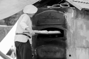 A baker places bread into a stone oven
