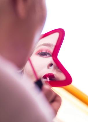 A woman does her make-up in a mirror
