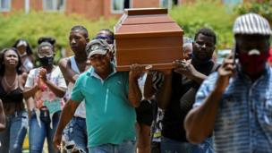 Hombres cargando uno de los ataúdes de los cinco adolescentes asesinados en Cali.