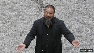 Ai Weiwei poses with his installation Sunflower Seeds at the Tate Modern gallery in London in October 2010
