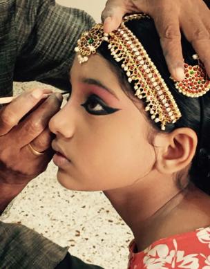 A young girl has eyeliner applied