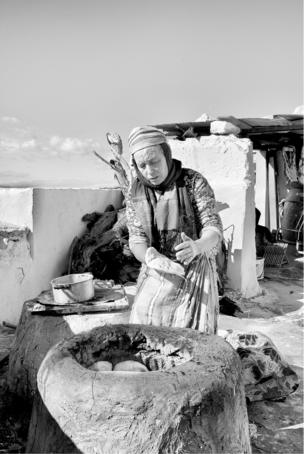 A woman prepares flatbread in an outdoor kiln