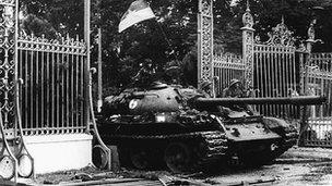 A North Vietnamese tank drives through the main gate of the presidential palace