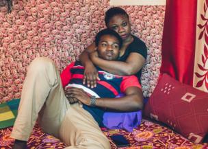 A couple sit on a bed