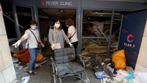 A woman wearing a face mask pushes a wheelchair at a damaged hospital following Tuesday"s blast in Beirut Lebanon August 5, 2020.