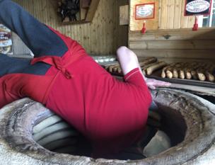A baker leans into a bread oven