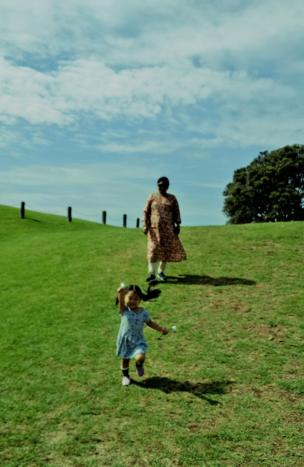 A young girl runs in front of her grandmother in a field