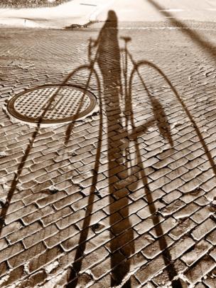Shadow of a man on a bike on a cobbled road