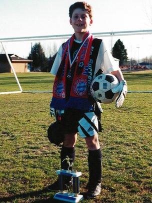 Adam Maier-Clayton as a child, posing with soccer trophies