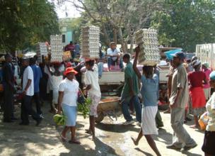 In a busy market, people carry towering egg cartons on their heads
