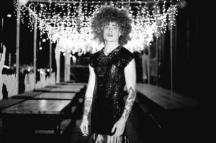 A candid photo of a drag queen smoking in an empty room