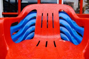 Stacked red and blue chairs are wet from the rain