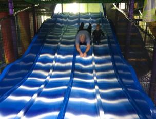 A granddad and his grandson whizz down a slide.