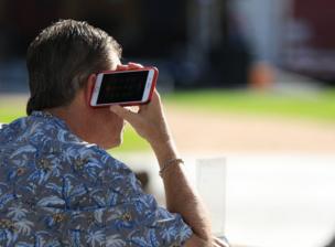 A person holds a mobile phone that is facing the wrong way up to his ear