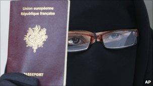 A Muslim woman in full face veil holds up her French passport at a conference near Paris, May 2010