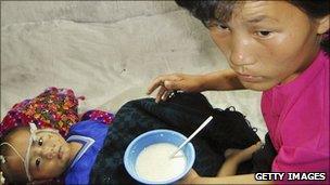 A malnourished boy is fed vitamin-enriched porridge provided by the World Food Programme (2004)