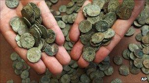British Museum staff member displays a handful of the coins