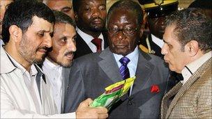 Mahmoud Ahmadinejad (l) and Robert Mugabe (c) inspect produce at a trade fair