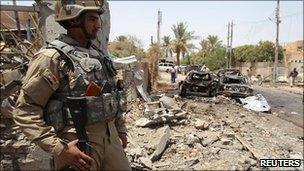 An Iraqi soldier stands guard at the site of a bomb attack in Baghdad, 26 July 2010