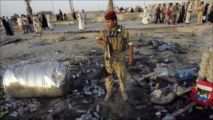 An Iraqi soldier stands guard at the site of a bomb attack in Kerbala, 27 July 2010