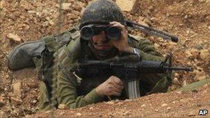 Israeli soldier uses binoculars near the disputed border area with Lebanon, August 4, 2010.