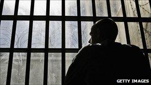 A prisoner staring through bars in an English jail