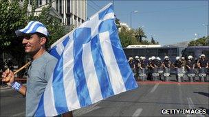 A trucker on strike holds a Greek flag in front of the Greek Parliament on July 30, 2010 during their protest march in Athens