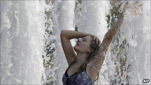 A woman cools herself in a fountain on Moscow's Poklonnaya Hill, 12 August