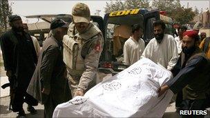 A Frontier Corp officer and rescue workers move the body of a victim killed by unidentified gunmen to a hospital in Quetta