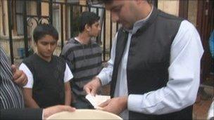 Man giving cash donation outside mosque