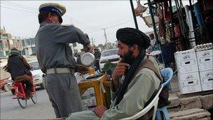 Policeman buys tea in Lashkar Gah in March 2010