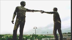 Statue of two men reaching out to each other.