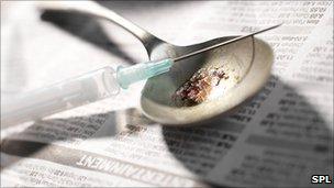 A hypodermic needle and syringe with heroin on a spoon