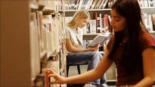 Two girls in a library looking at books