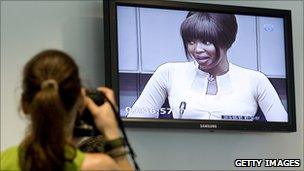 A photographer takes a picture of Naomi Campbell on screen
