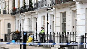 A PCSO stands outside a building where the body of an unnamed man was discovered in a top floor apartment