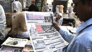 A man reads a newspaper report about the scandal in Lahore