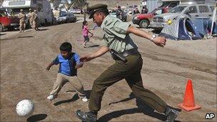 A police officer and child play football at the camp where relatives of trapped miners wait for news in Copiapo, Chile on Sunday