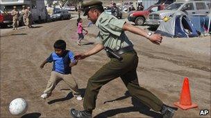 A police officer and a child play football at the camp where relatives of trapped miners wait for news outside the San Jose in Copiapo, Chile