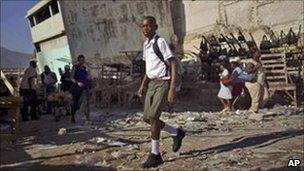A student walks past damaged buildings in Haiti's capital Port-au-Prince. Photo: October 2010