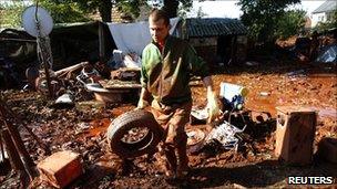 Resident of the flooded village of Devecser cleans up a yard covered in toxic sludge, 11 October 2010