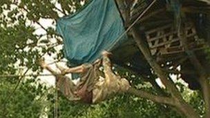 A protester climbing a rope to a tree house