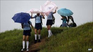 Students in Pinar del Rio cover themselves from the rain