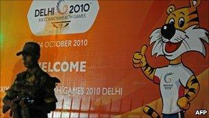 Indian policeman stands guard beside a banner for the 2010 Commonwealth Games outside a hotel in New Delhi on 1 October 2010